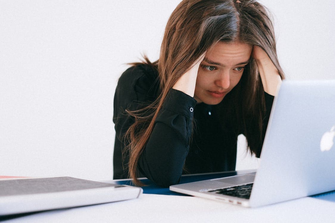 Mulher estressada olhando para a tela de um laptop com expressão de frustração diante de problemas no site